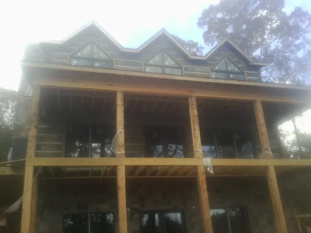 Dormers and porch framing on a large log home under construction — Roof Coating work by our crew in Fenwick Island