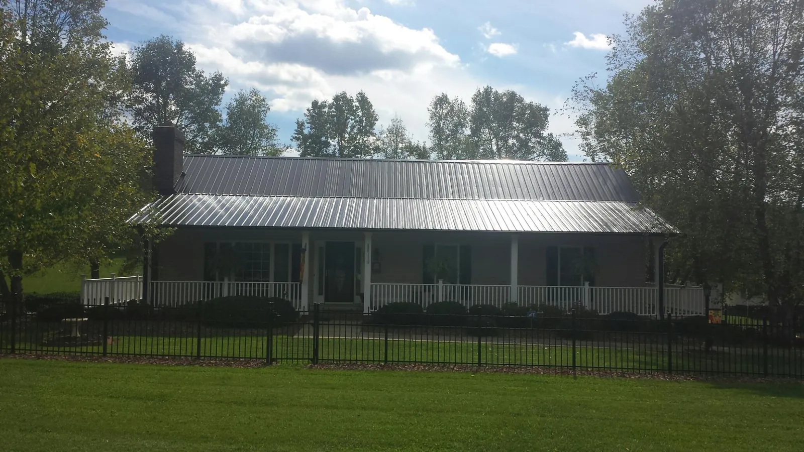Gray metal roof on a brick ranch with a full width front porch — Gutter Guard Installation work by our crew in Fenwick Island