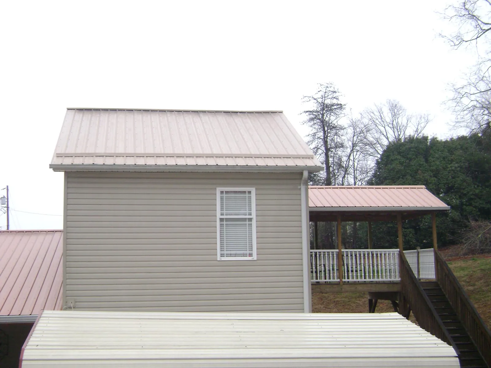 Tan metal roofs on a two story addition and attached porch, from a Roof Replacement job in Fenwick Island