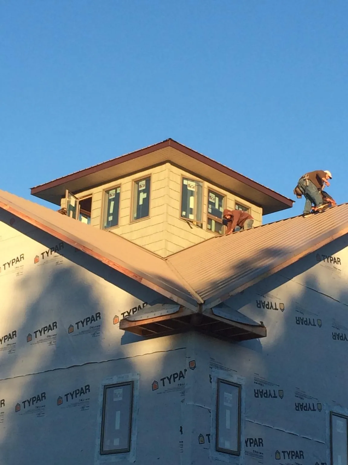 Roofers working around a rooftop cupola on a new metal roof at sunset — Roof Waterproofing in Fenwick Island by Roofing Brothers